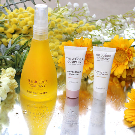 Skincare products from The Jojoba Company with flowers in the background