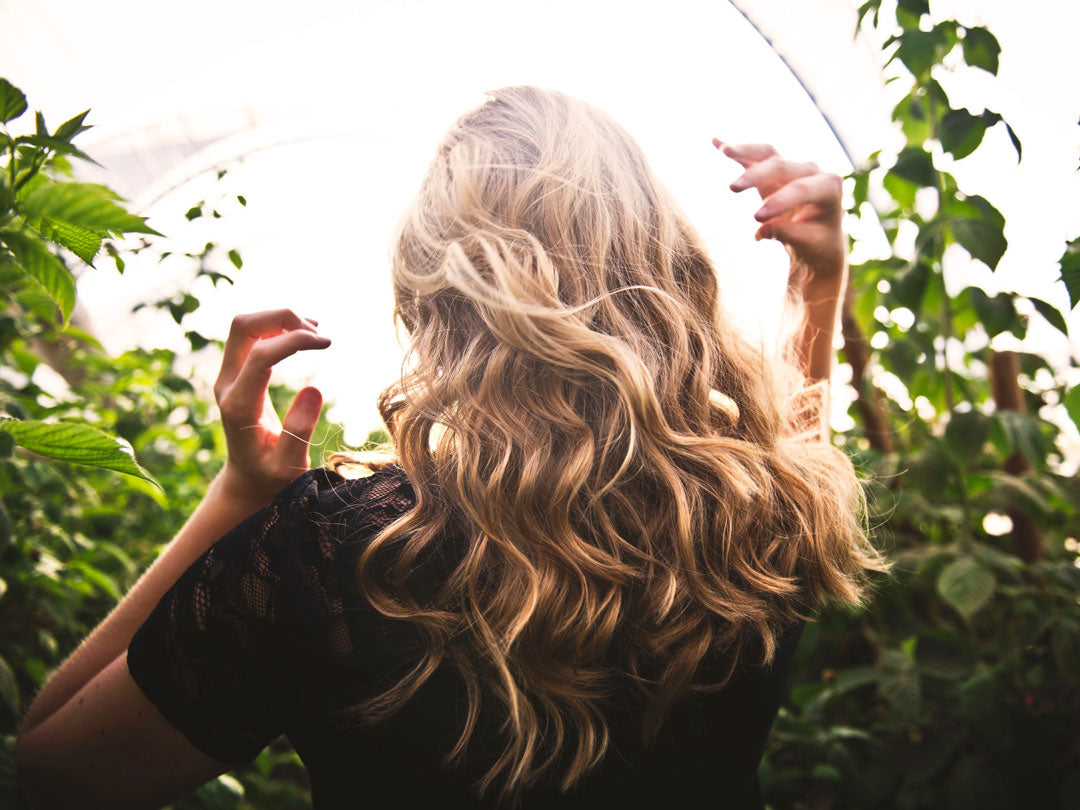 Woman with curly blonde hair holding a transparent umbrella in sunlight.