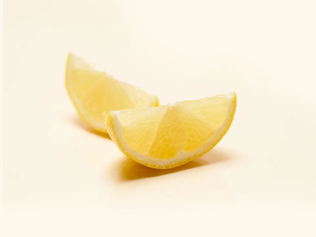 Two lemon wedges on a pale background.