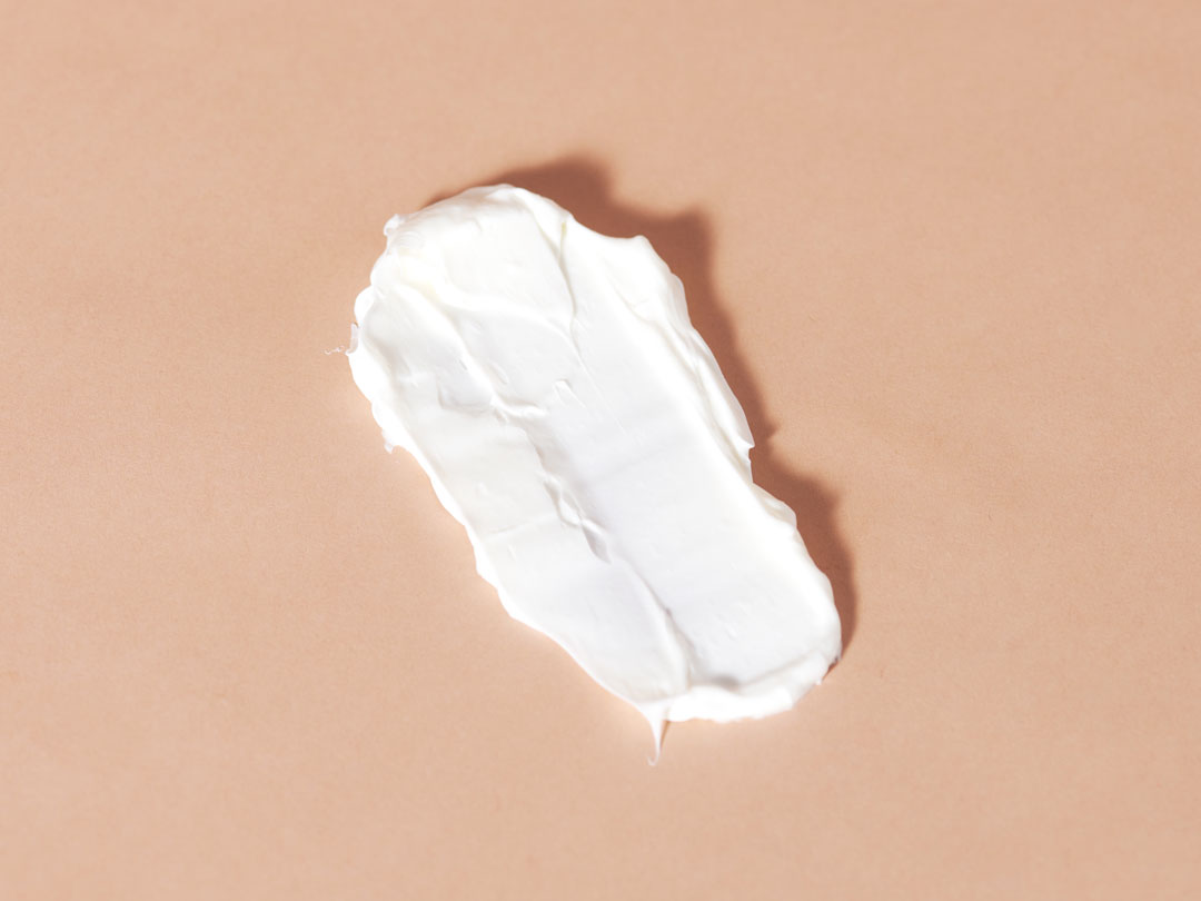 A smear of white cream on a beige background.