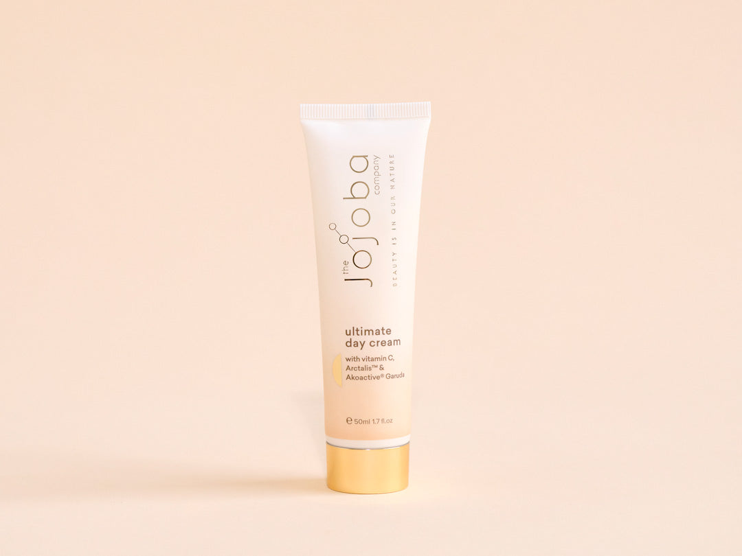 A tube of ultimate day cream with vitamin C on a beige background.