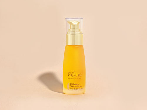 Bottle of Jojoba Ultimate Youth Potion skincare product on a beige background.