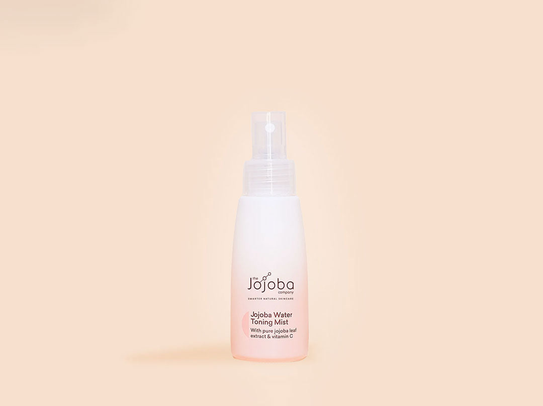 A bottle of Jojoba Water Toning Mist against a peach background.