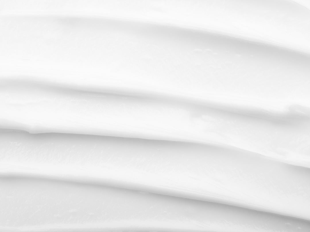 Close-up of a white cream texture with smooth, wavy lines.