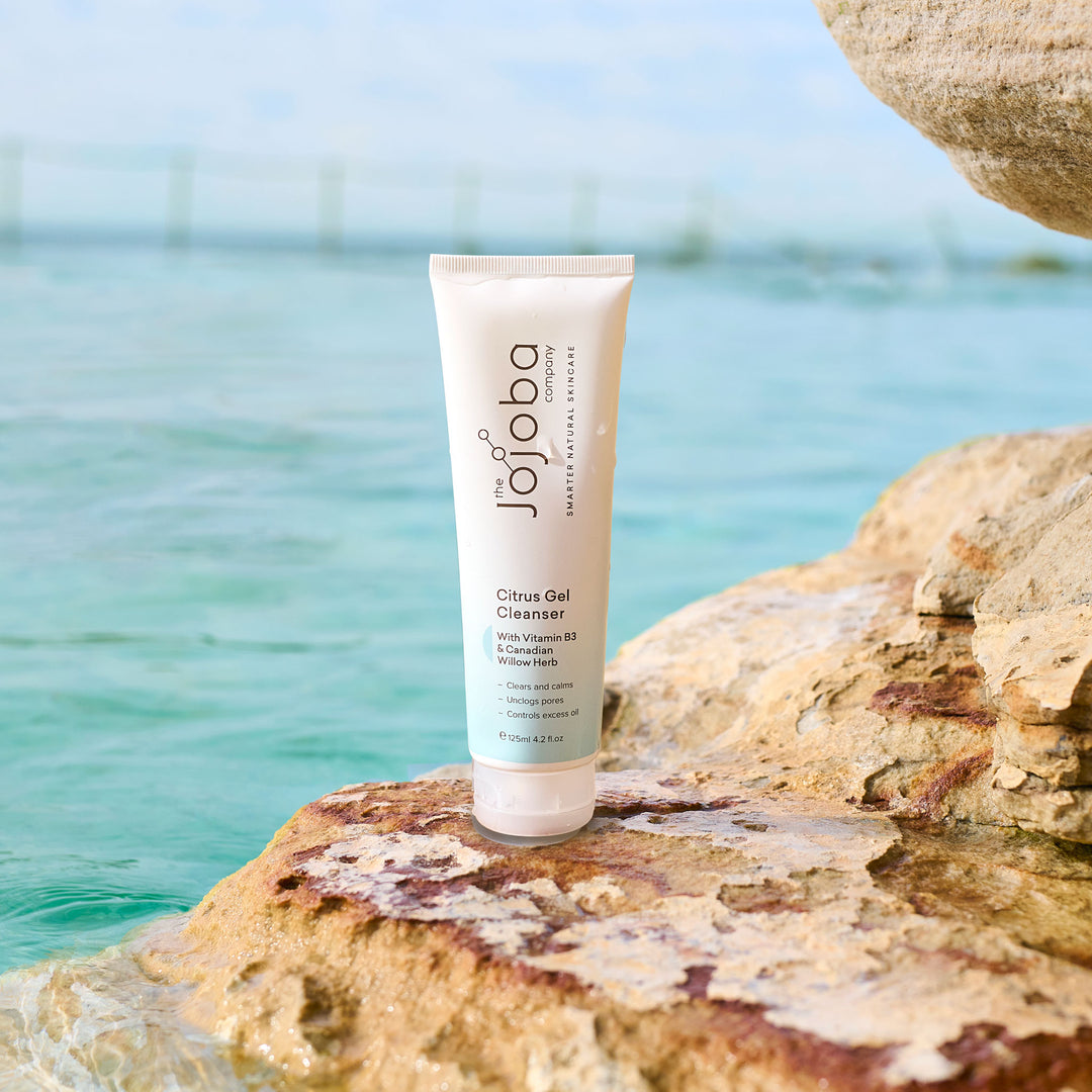 Tube of Jojoba Citrus Gel Cleanser on a rock by the water.